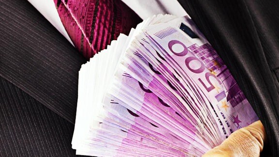 Mann steckt 500-Euro-Scheine in Jackett