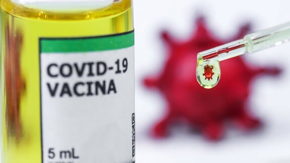 Ampulle mit der Aufschrift 'Covid-19 Vacina' und ein Coronavirus, der sich in einem Tropfen spiegelt.