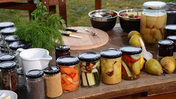 Auf einem Tisch stehen viele Gläser mit eingewecktem Obst und Gemüse.