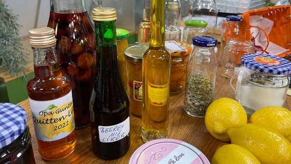 Flaschen, Marmeladengläser und Obst stehen auf einem Tisch.