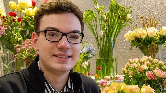 Quentin Oberstedt - ein junger Mann mit Brille - arbeitet mit Blumen.