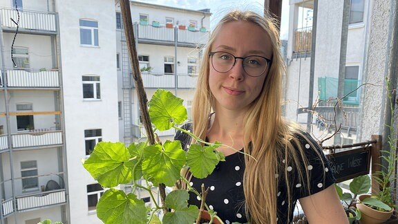Studentin Katharina mit Pflanzen in der Hand auf ihrem Balkon.