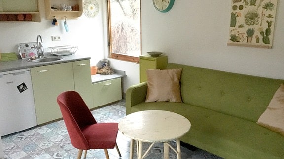 Eingerichtetes Zimmer in einer Gartenlaube mit Küche und Sofa