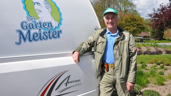 Jürgen Meister vor Camper: Ein Mann steht neben einem Campingwagen auf dem das Logo des Gartenmeisters zu erkennen ist. 