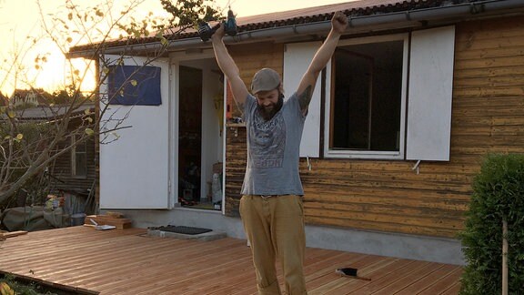 Frank Krause steht erfreut auf der fertigen Holz-Terrasse
