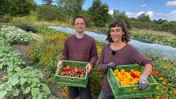 Ference Benke und Elise Marwitz von der Gemüsebande Weimar halten Kisten mit Paprika und Tomaten in den Händen