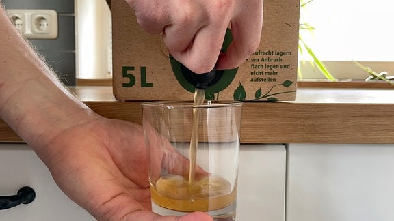Apfelsaft wird in ein Glas eingeschenkt.