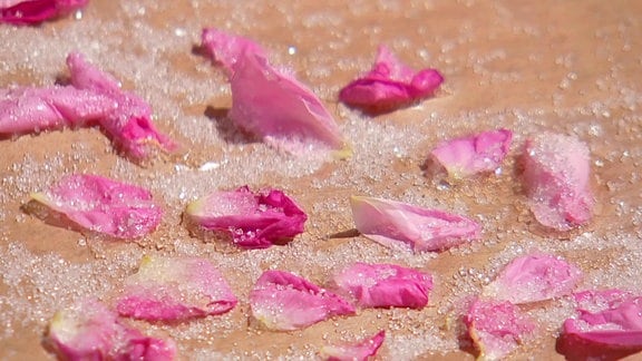 Kandierte Rosenblütenblätter liegen auf Butterbrotpapier