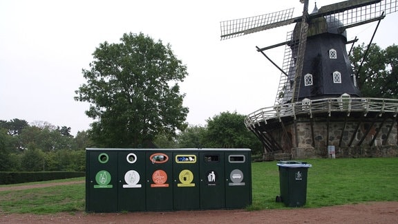 Öffentliche Müllcontainer in einem Park vor einer Windmühle in Malmö in Schweden.   