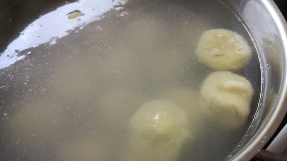 Pflaumenknödel kochen – Knödel schwimmen in einem Topf mit Wasser  
