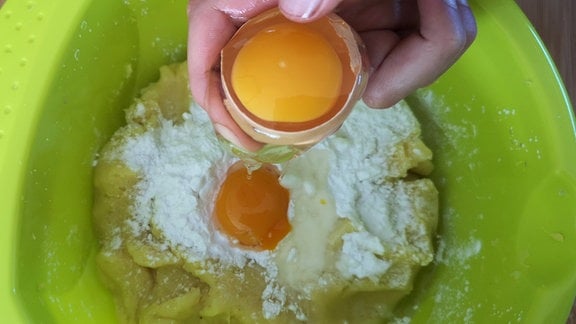 Pflaumenknödel Zutaten – In eine Backschüssel mit Kartoffeln und Mehl wird ein Ei geschlagen