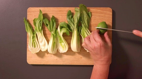 Pak Choi Salat wird auf einem Brettchen geschnitten