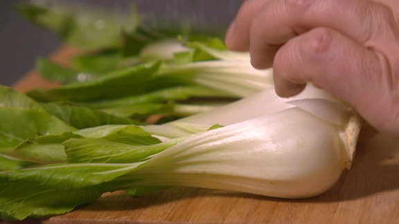 Pak Choi Salat wird auf einem Brettchen geschnitten