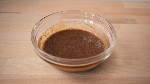 Brauner Sirup in einer Glasschale auf einem Holztisch