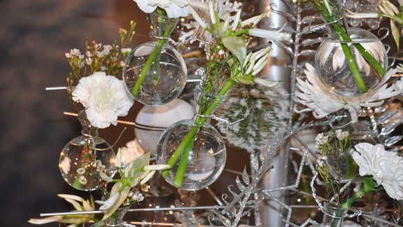 Blumen in Glaskugeln an einem Weihnachtsbaum.