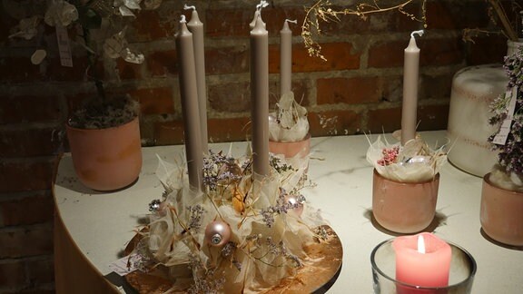 Adventskranz mit Schleierblättern, rosanen Weihnachtskugeln, Blüten und braunen Stabkerzen