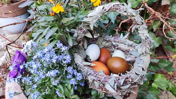 Ein aus Salbei geflochtener Krob mit Eiern und Blumen.