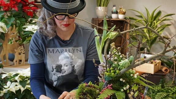 Floristin Franziska Rühle arbeitet an Baumstamm mit Nägeln und Blumen