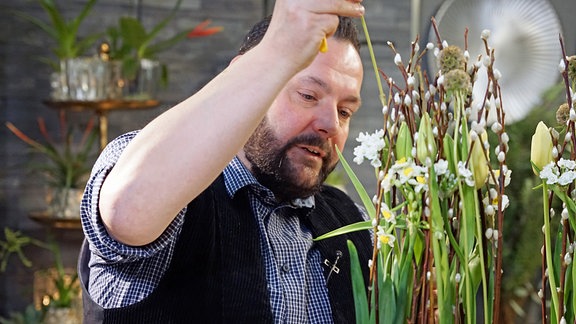 Florist Thorsten Wösthaus arbeitet an Gesteck mit Blumen und Weidenzweigen