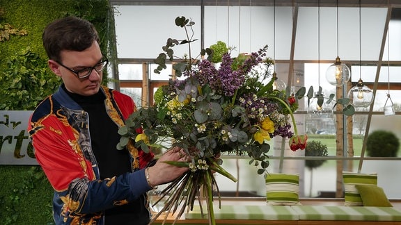 Florist Quentin Oberstedt bindet einen Frühlingsstrauß.  