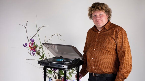 Ein Mann vor einem mit Blumen geschmückten Schallplattenspieler
