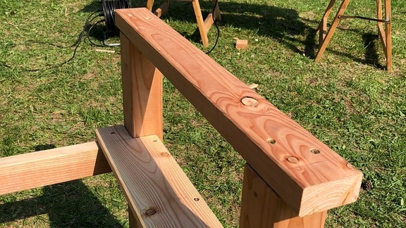 Armlehne einer Holzbank mit Sitzfläche, die noch nicht fertig montiert ist.