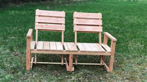 Eine Holzbank für zwei Personen mit verstellbaren Lehnen.