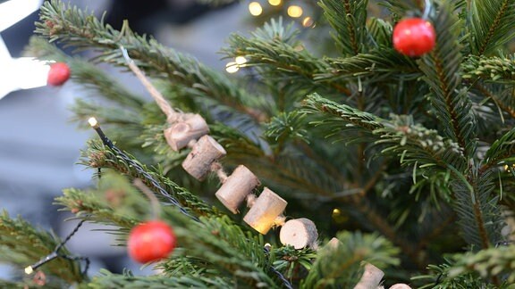An einem Weihnachtsbaum hängt eine Holzgirlande 