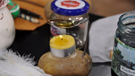 Kartoffel mit Teelicht, Löffel und flüssigem Wachs