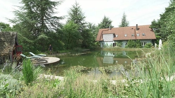 Ein Schwimmteich, im Hintergrund ein Haus