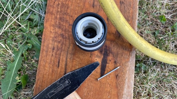 Die Materialien für einen selbst gebauten Tropfschlauch: Ein Hammer, ein Nagel, ein alter Schlauch, ein Schlauchverbinder mit Wasserstopp-Funktion.