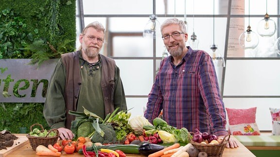 Jörg Heiß und Martin Krumbein stehen hinter einem Tisch mit verschiedenen Gemüsesorten.