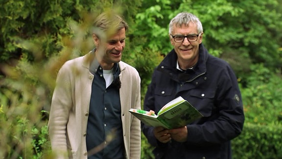 Horst Schöne lächelt und hat ein Buch in der Hand.