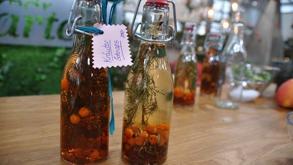 Zwei Glasflaschen mit selbstgemachtem Kräuterschnaps mit Vogelbeeren.