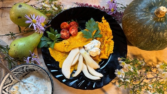 Mit Tomaten, Gemüse und Kräutern dekorierter Pfannkuchen auf Teller