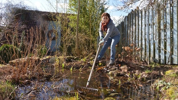 Gärtnerin Brigitte Goss säubert einen Teich