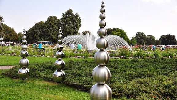 Skulpturen aus Metallkugeln vor einem Springbrunnen