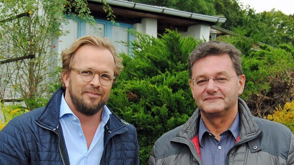 Moderator Jens Haentzschel und Rechtsanwalt Volkmar Kölzsch stehen vor einem Gartenhaus  