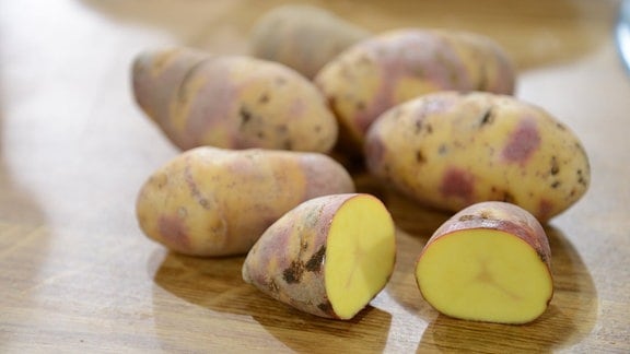 Auf einem Tisch liegt die Kartoffelsorte Mayan Twilight. Das besondere ist die gelb-violette Farbe der Schale.   