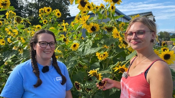 Melanie Trinks und Martha Berghold stehen vor großen Sonnenblumen im Egapark Erfurt.