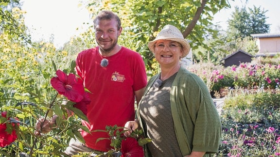 Staudengärtner Pascal Klenart und Moderatorin Diana Fritzsche-Grimmig stehen neben einem Staudenhibiskus.