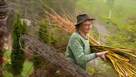 Eine Frau trägt ein Bündel mit Weidenruten 