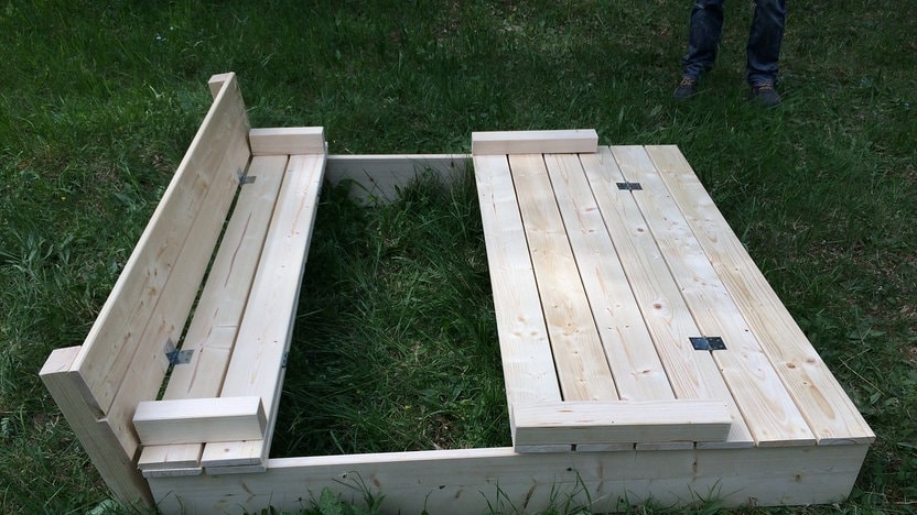 How Do You Build A Sandbox With A Lid And Bench? 4 Blick auf einen Sandkasten mit halb geschlossener Abdeckung und integrierter Bank.