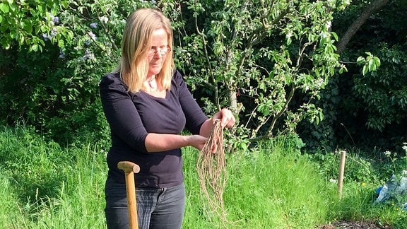 Eine Frau steht an einem Beet und hat einen Graben ausgehoben