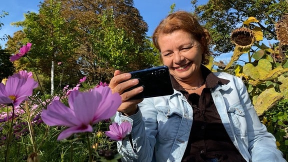 Gartenexpertin Brigitte Goss schaut auf ein Smartphone