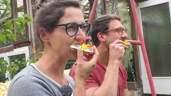 Fabian Fröderking und Reporterin Nadine Witt essen eine Stulle mit geernteten essbaren Blüten.