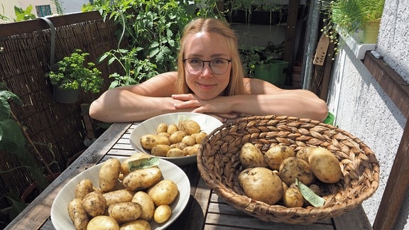 Balkongärtnerin mit drei Schalen erntefrischer Kartoffeln