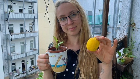 Balkongärtnerin Katharina Koch hält Mini-Zitronenbaum in Topf und Zitrone