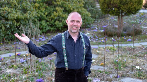 Oliver Richter steht in seinem Garten mit Frühblühern