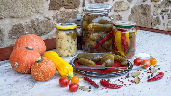 Traumgarten in Saalfeld: Ernte konservieren - Kürbis, Zucchini, Tomaten und Gläser mit eingewecktem Gemüse stehen auf einem Tisch